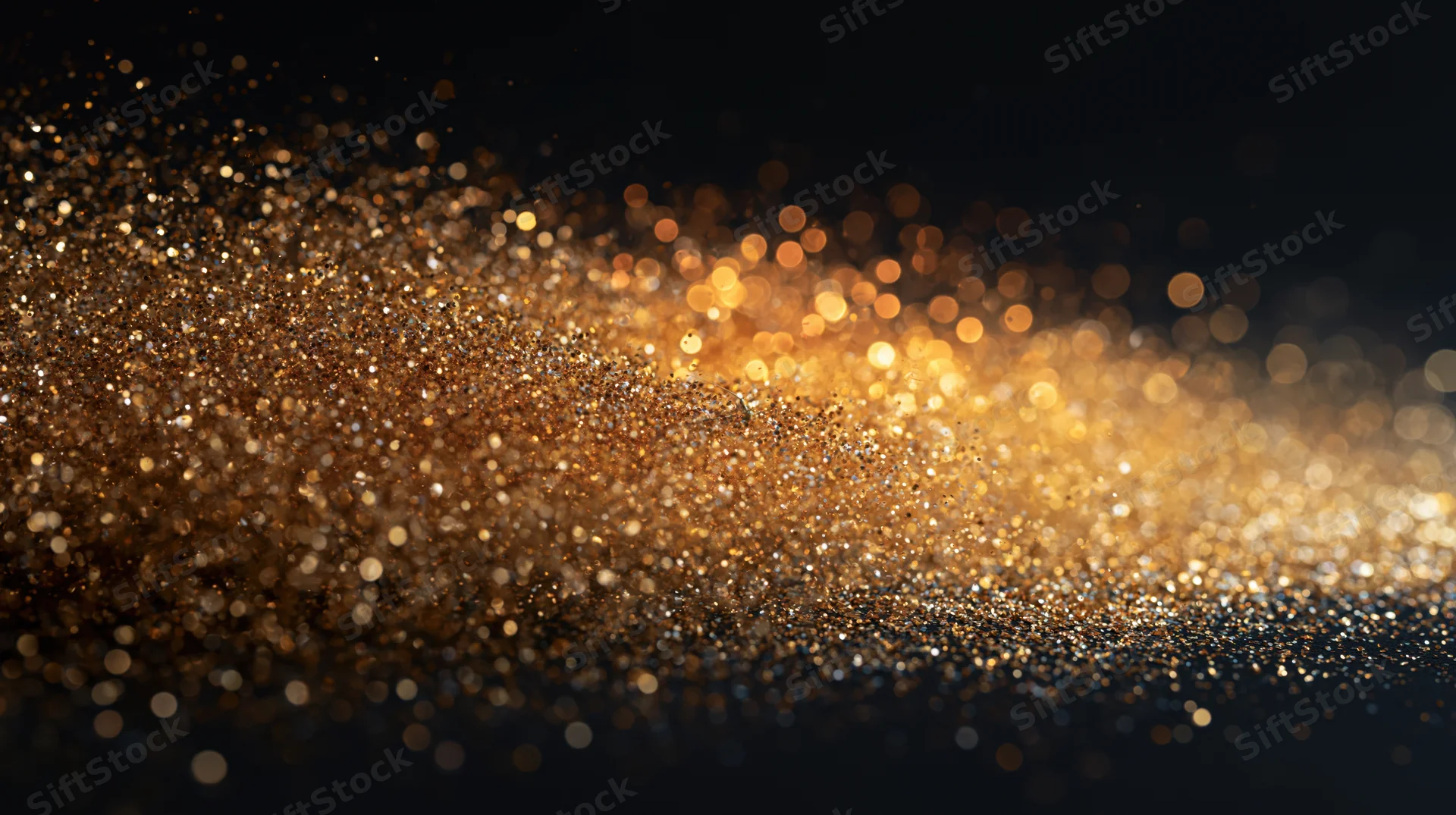 Golden glitter particles scattering in motion against a dark background