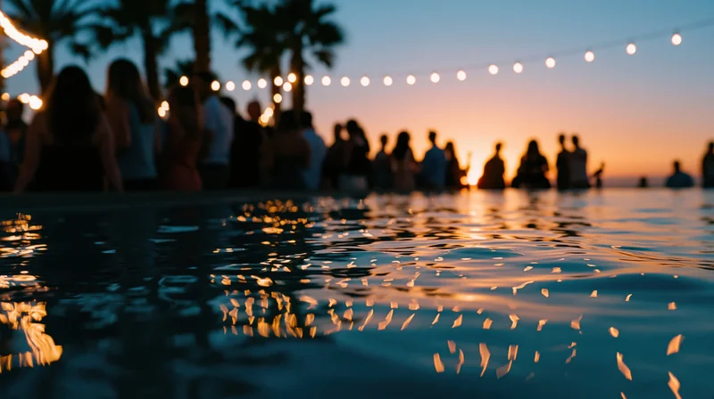 Twilight party by a pool with string lights and palm trees reflected in the water