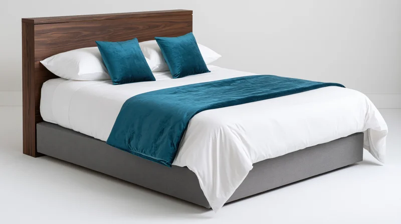 Double bed with white linens and teal velvet accents against plain white background