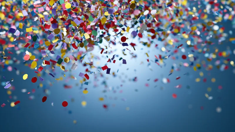 Multicolored paper confetti falling against a blue sky background with copyspace at the bottom