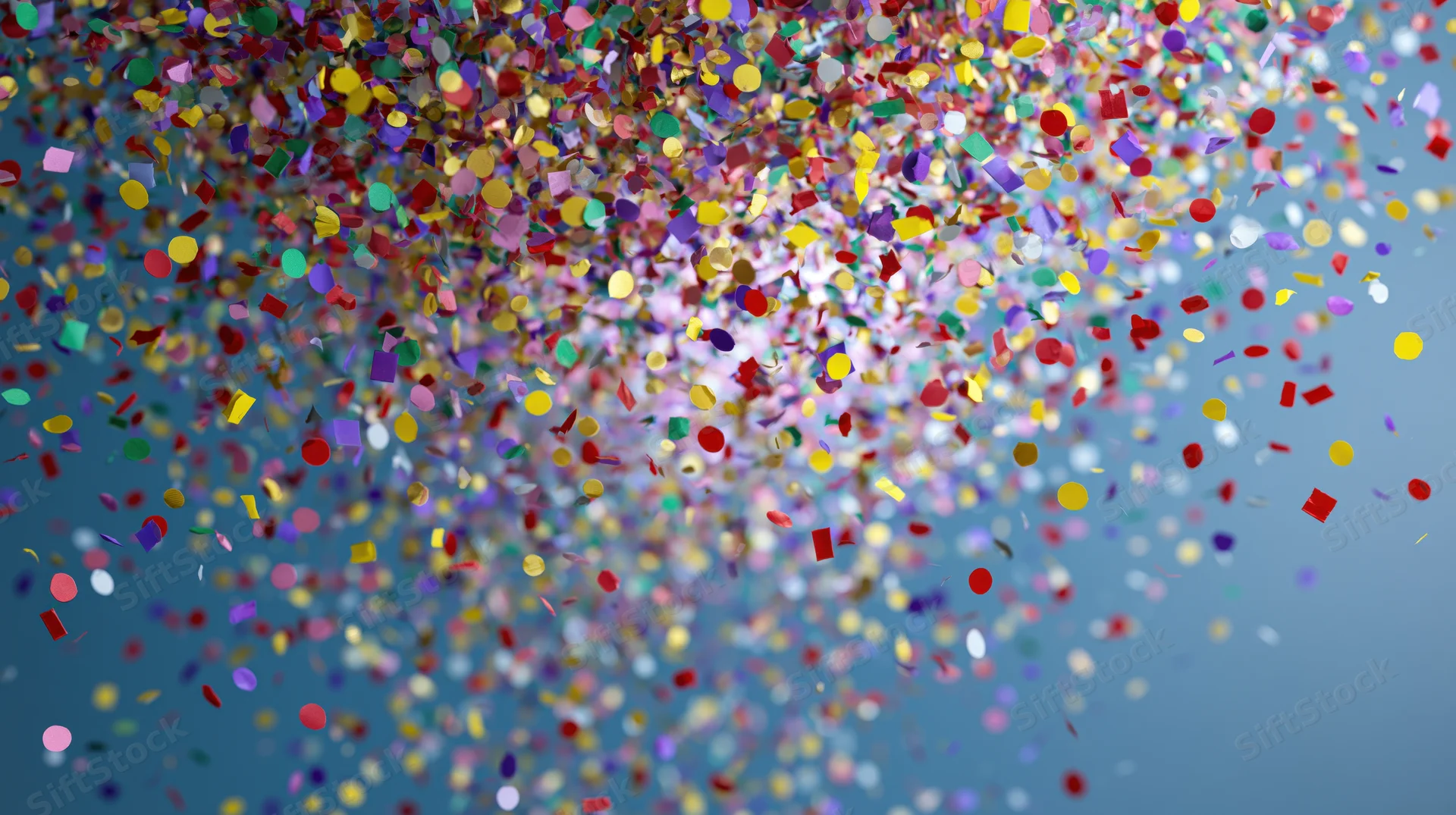 Multicolored paper confetti falling midair against a blue background