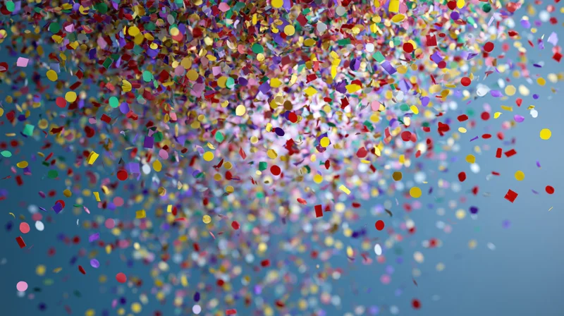 Multicolored paper confetti falling midair against a blue background