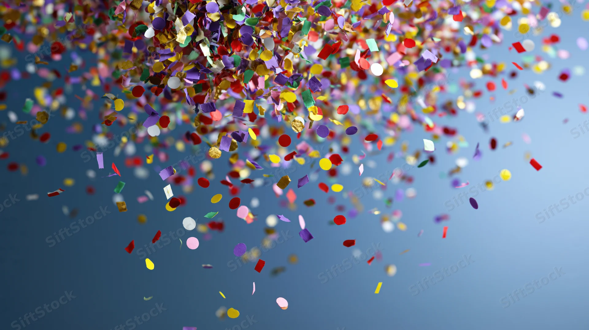 Multicolored paper confetti falling through the air against a blue background