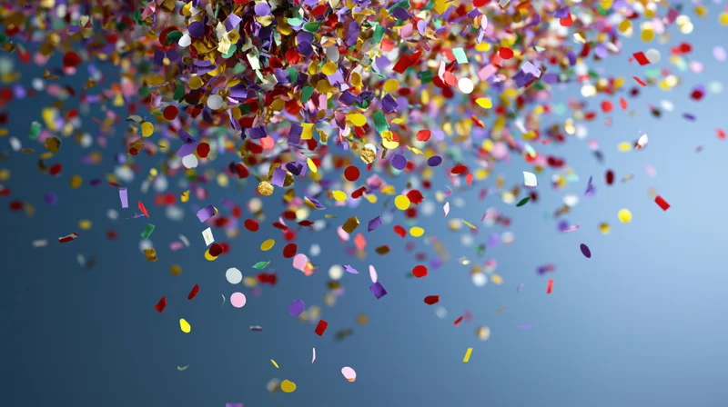 Multicolored paper confetti falling through the air against a blue background
