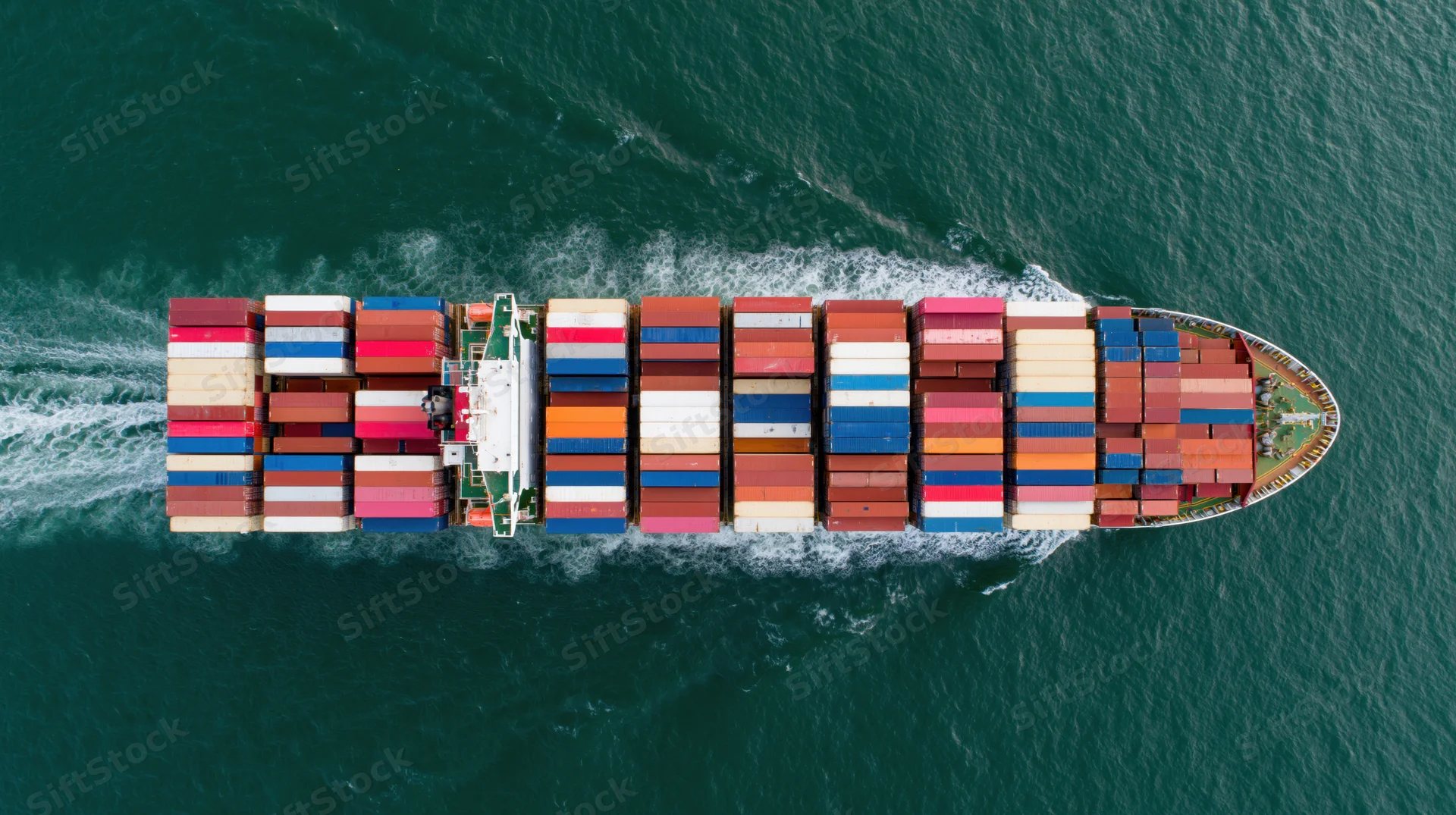 Overhead view of large container ship carrying stacked multicolored cargo containers on open ocean