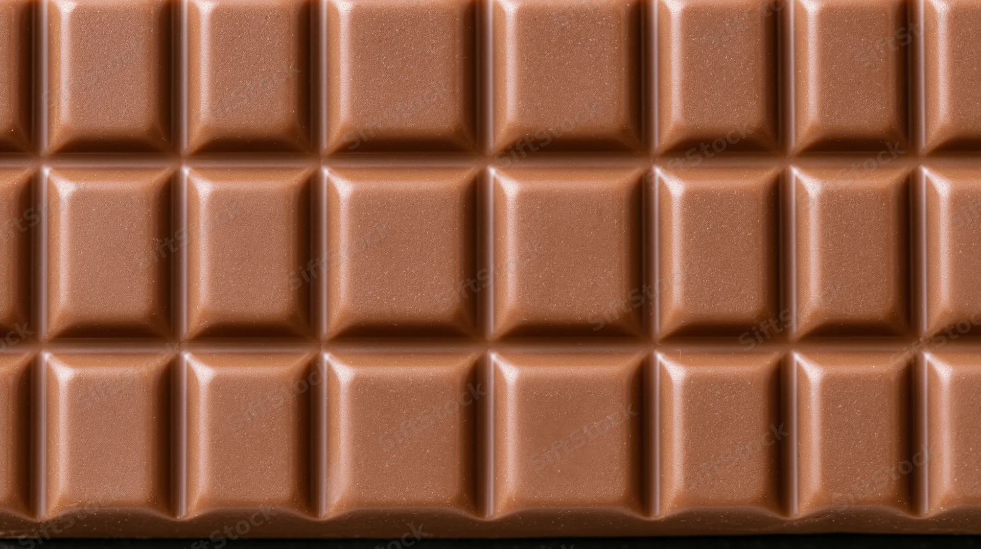 Closeup of milk chocolate bar with segmented grid pattern filling the frame