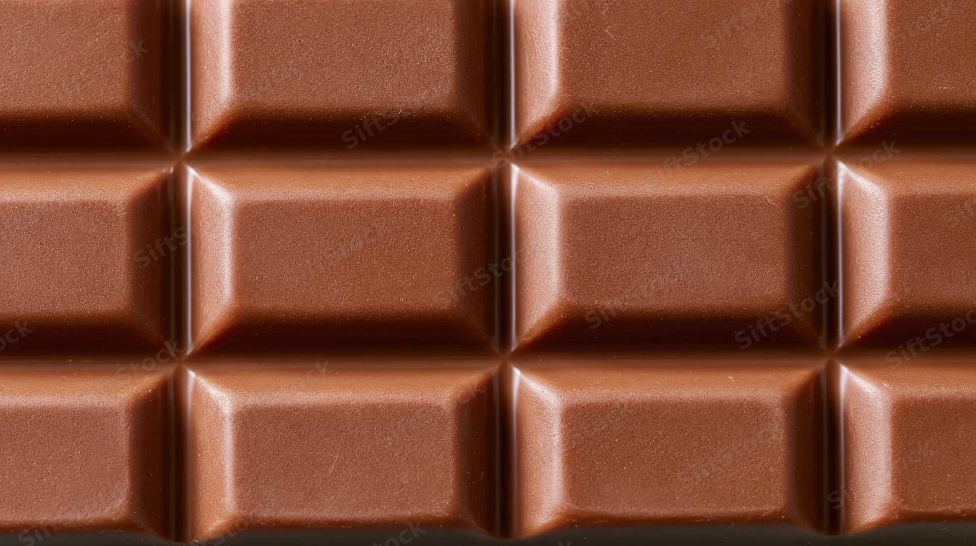 Closeup of milk chocolate bar surface with grid pattern filling frame