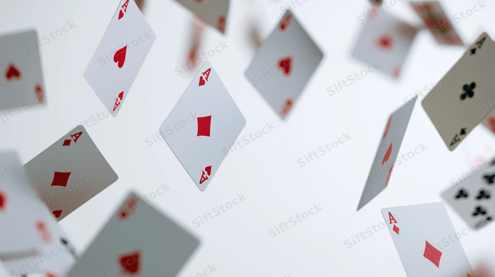 Aces of all four suits tumbling in mid-air against a white background