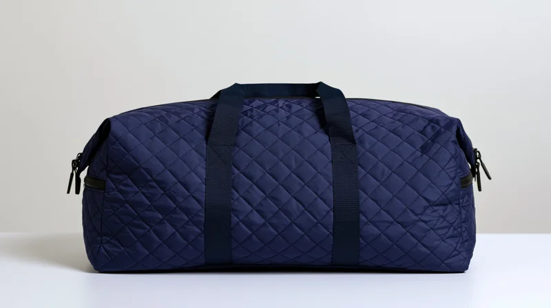 Navy blue quilted nylon duffel bag sitting upright on white surface