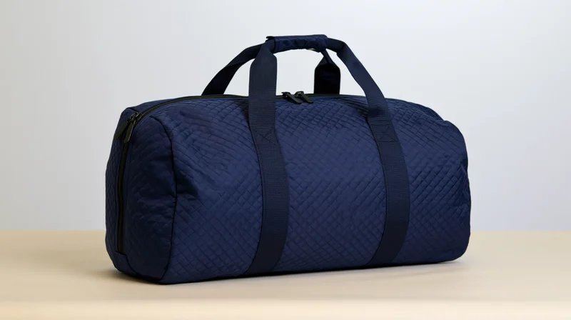 Navy blue nylon duffel bag with quilted texture and top handles sitting on a flat surface