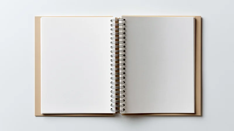 Open spiral-bound notebook with blank white pages lying flat on white surface