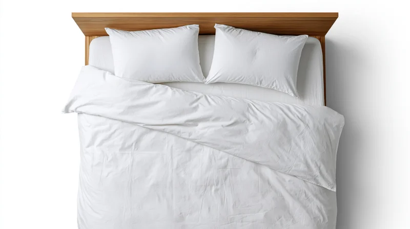 Overhead view of a neatly made double bed with white bedding and wooden headboard against a white background