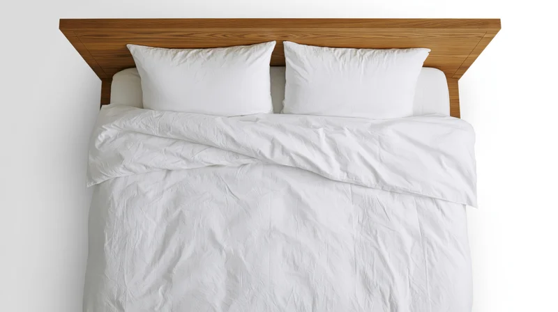 Overhead view of a double bed with white bedding and wooden headboard in a minimalist bedroom