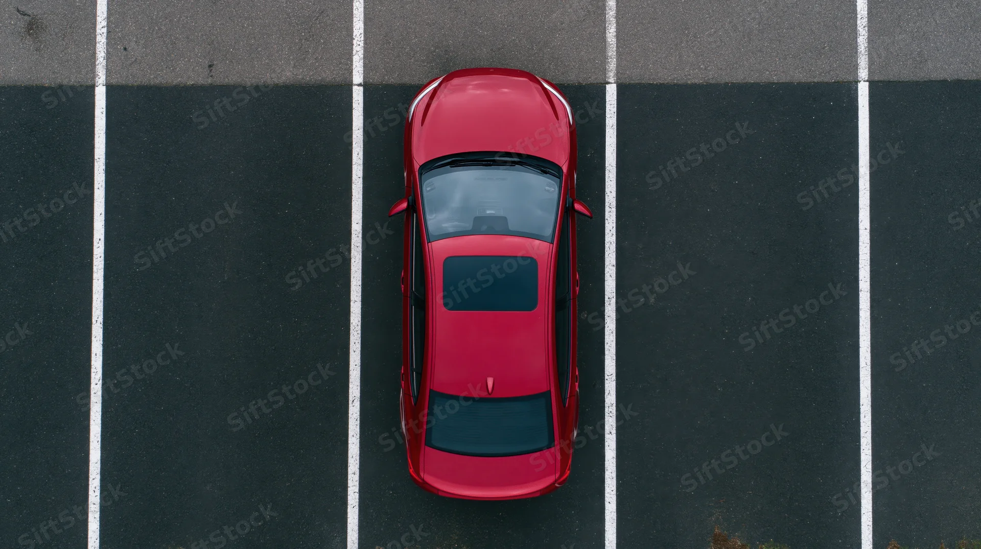 Red sedan parked alone in empty lot viewed from directly above