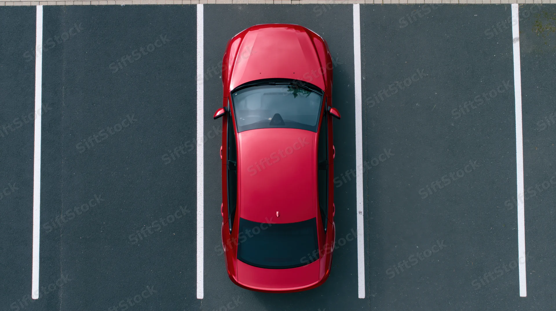 Red tesla sedan parked in an empty lot viewed from directly above