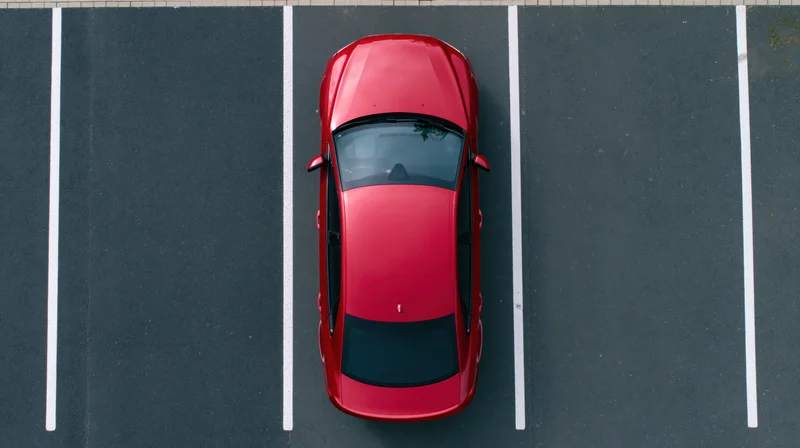Red tesla sedan parked in an empty lot viewed from directly above