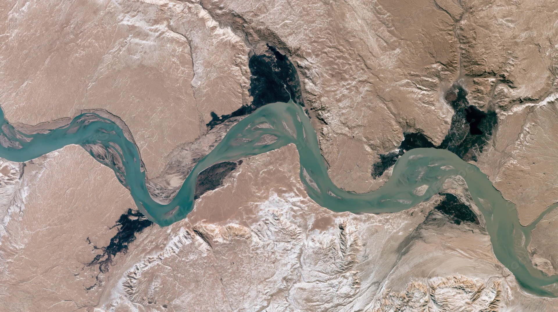 Winding river delta flowing through arid desert terrain from satellite view