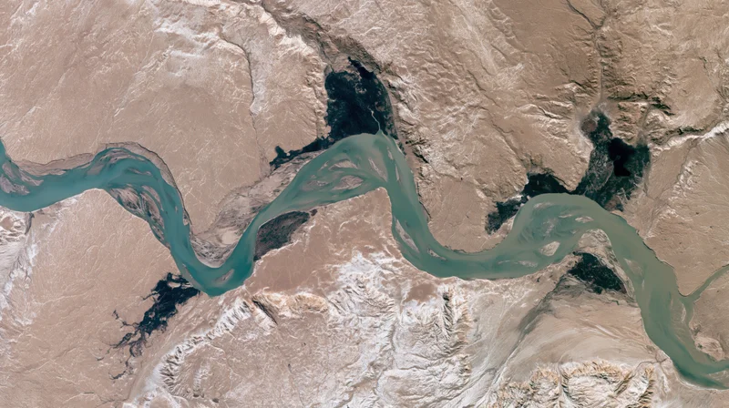 Winding river delta flowing through arid desert terrain from satellite view