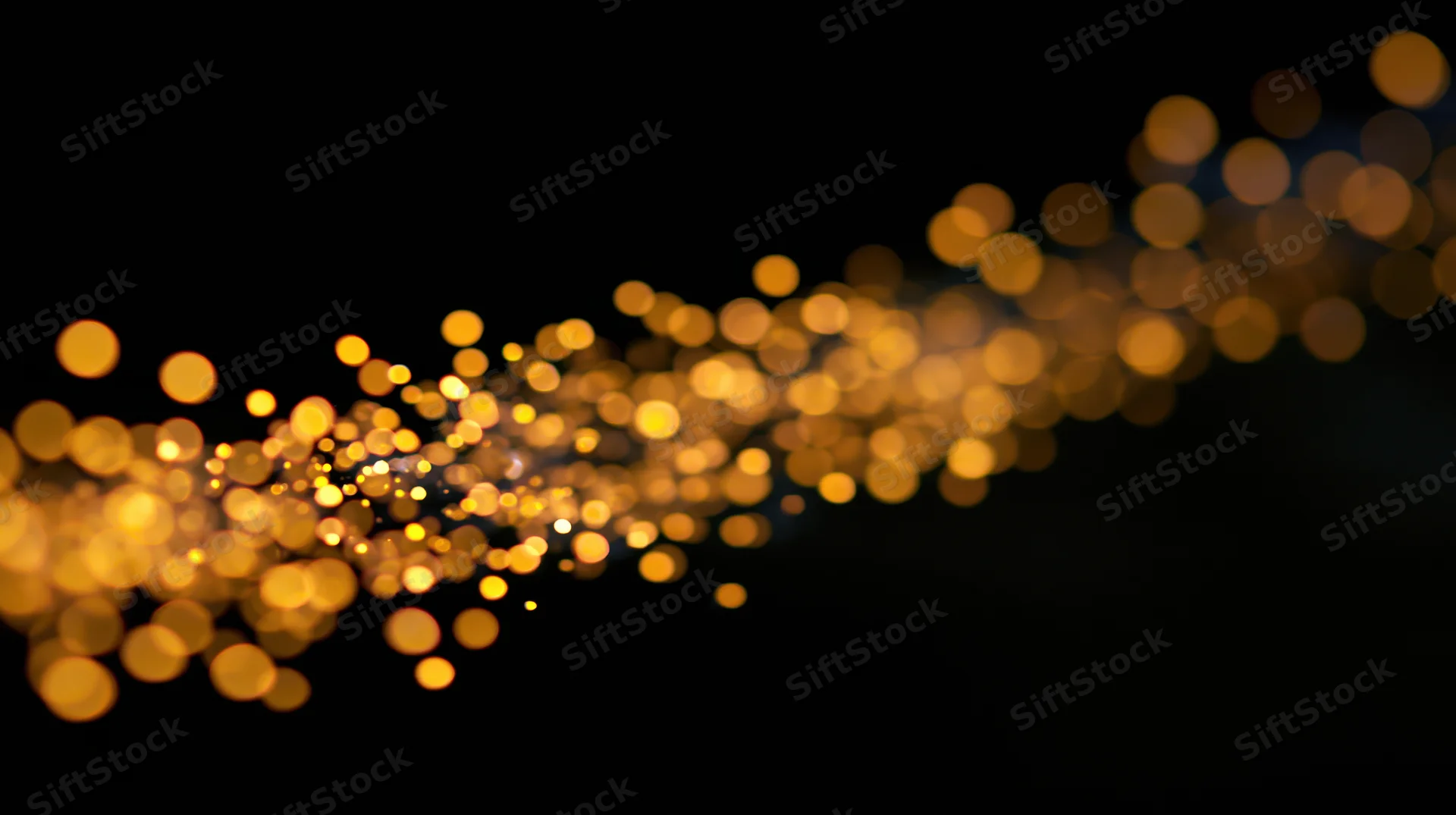 Golden bokeh lights drifting across a dark background with copyspace on the right