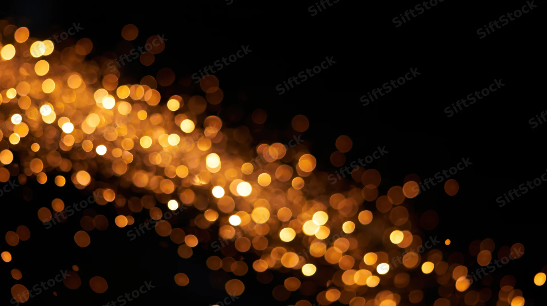 Golden bokeh light particles drifting across a dark background