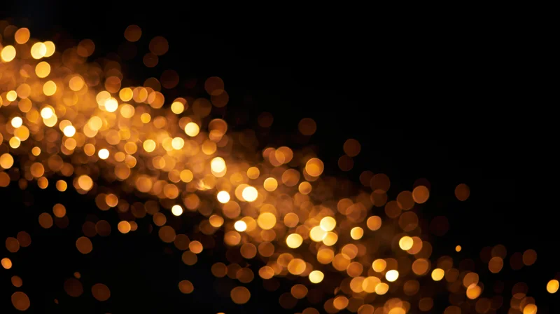 Golden bokeh light particles drifting across a dark background