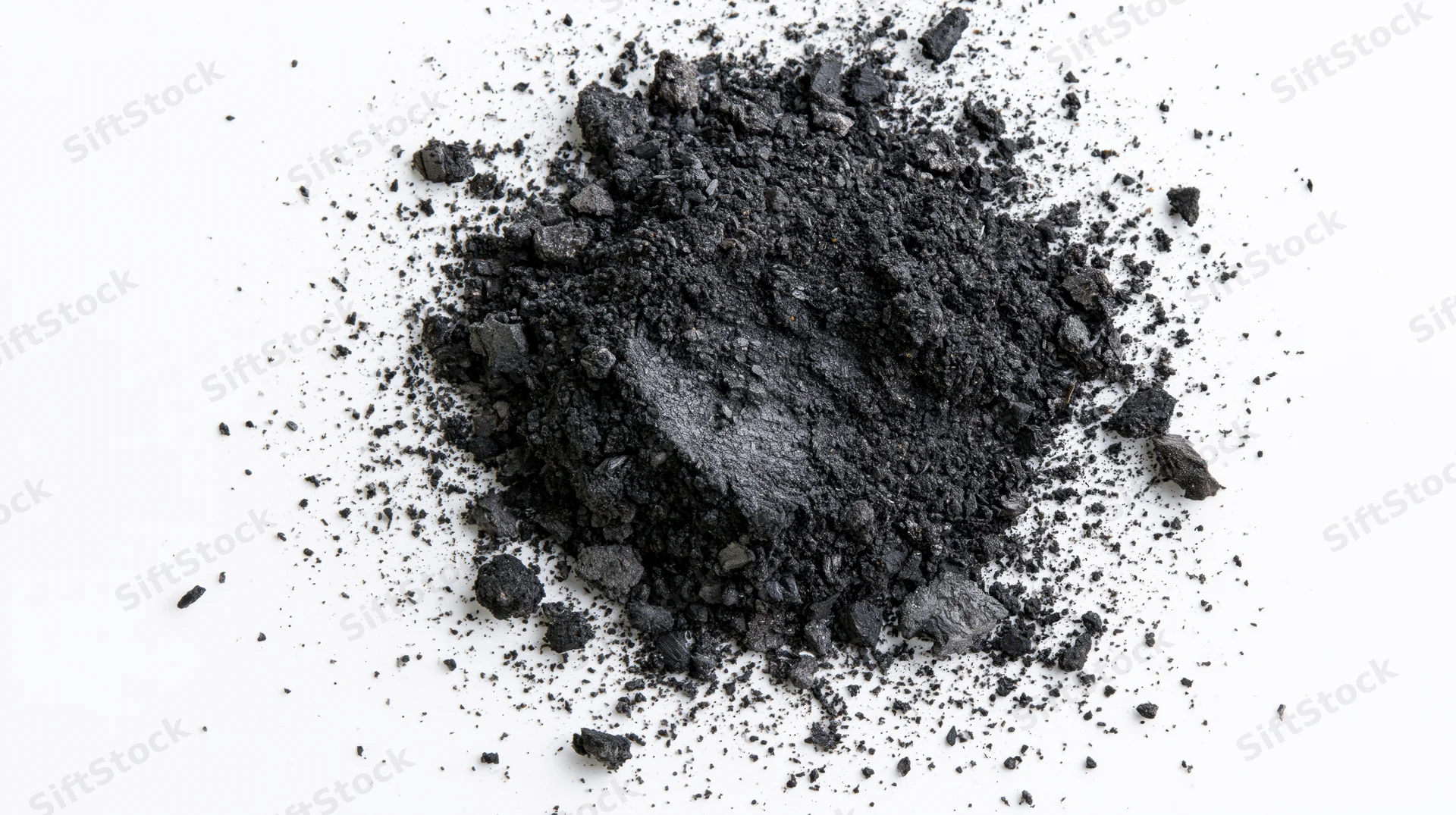Scattered pile of dark grey charcoal dust and crushed ash on white background