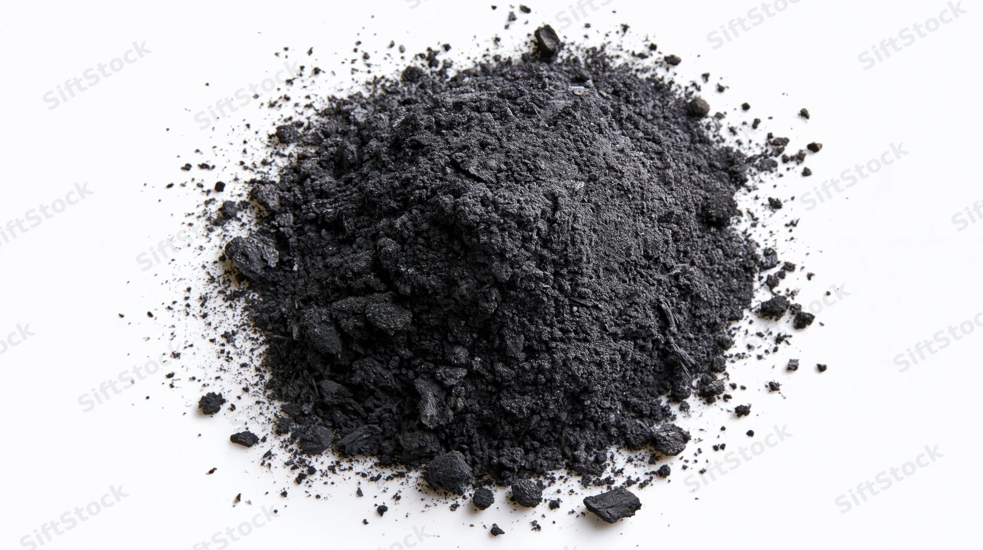Scattered pile of dark grey charcoal dust and crushed ash on white background