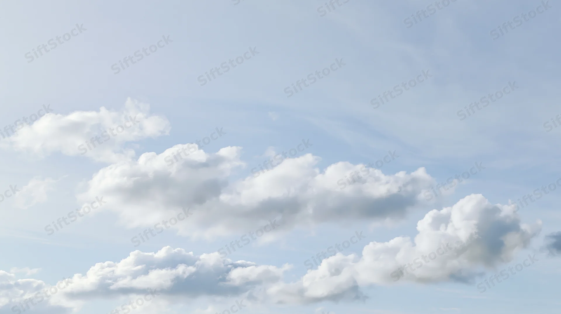 Scattered cumulus clouds drifting across a clear blue sky