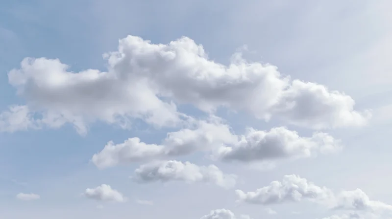 Scattered cumulus clouds drifting across a clear blue sky