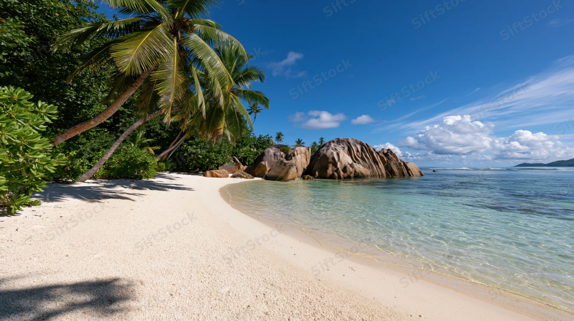 Curved white sand beach with palm trees and clear blue water under sunny sky