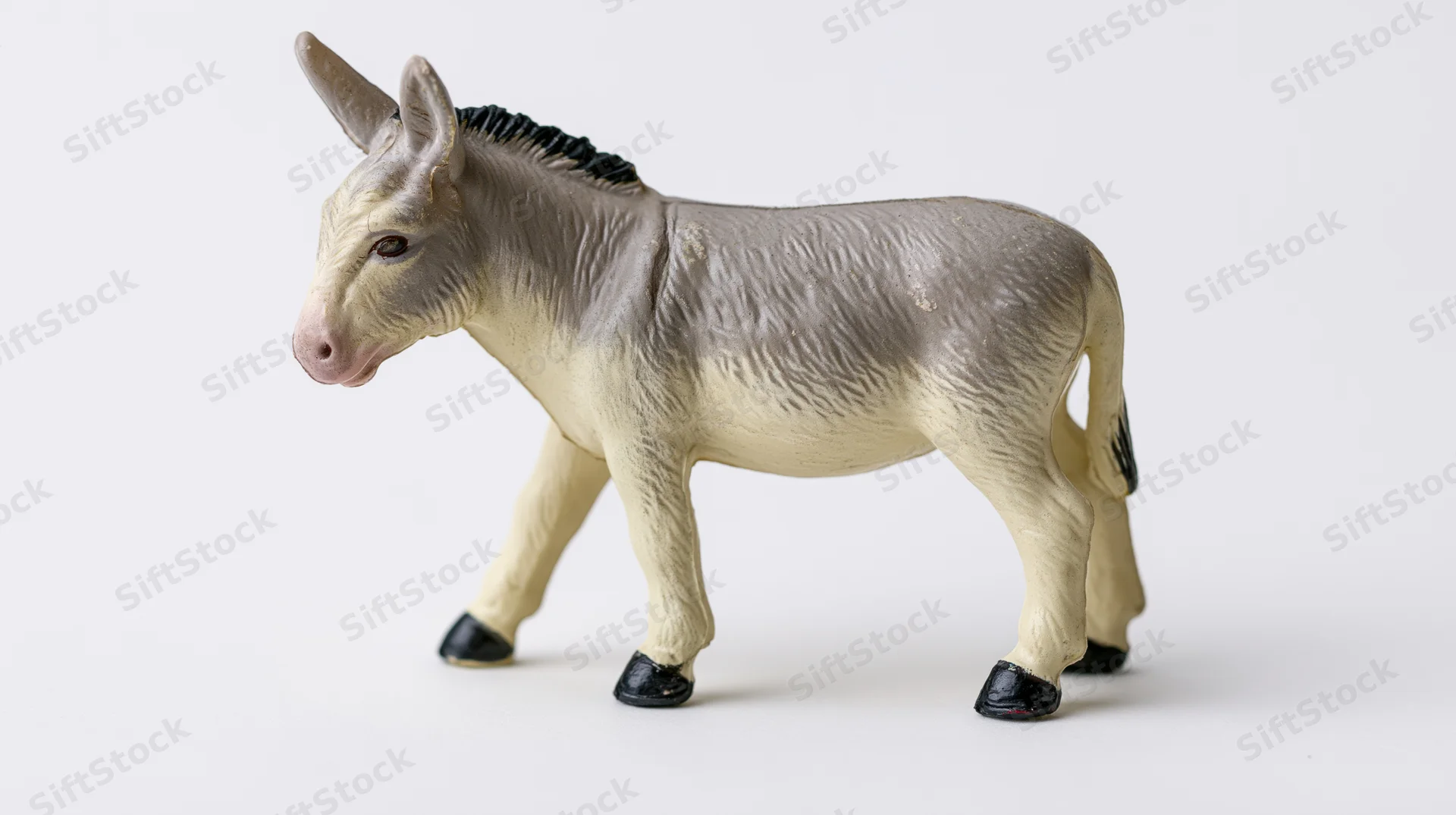 Small plastic donkey figurine standing in profile view on white background