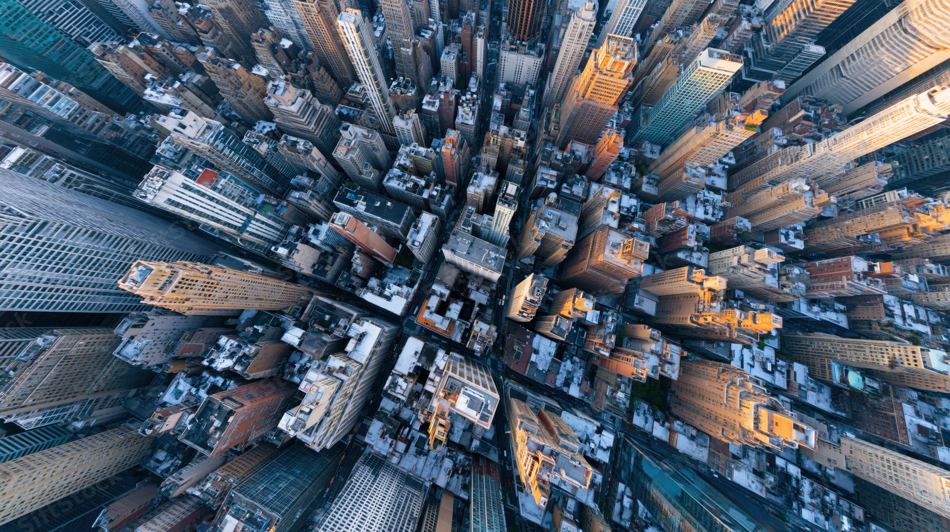 Straight-down aerial view of dense manhattan skyscrapers and buildings in golden hour light