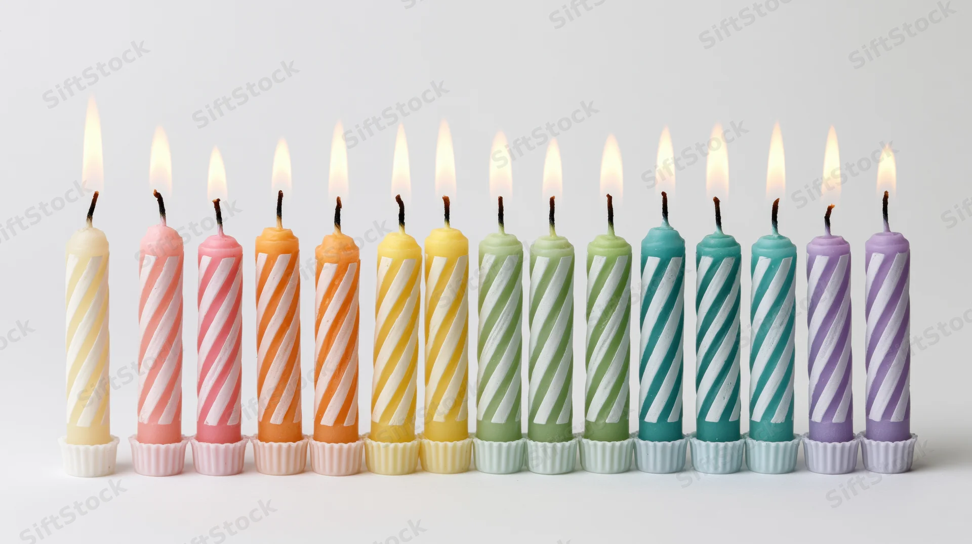 Row of lit colorful birthday candles on white background