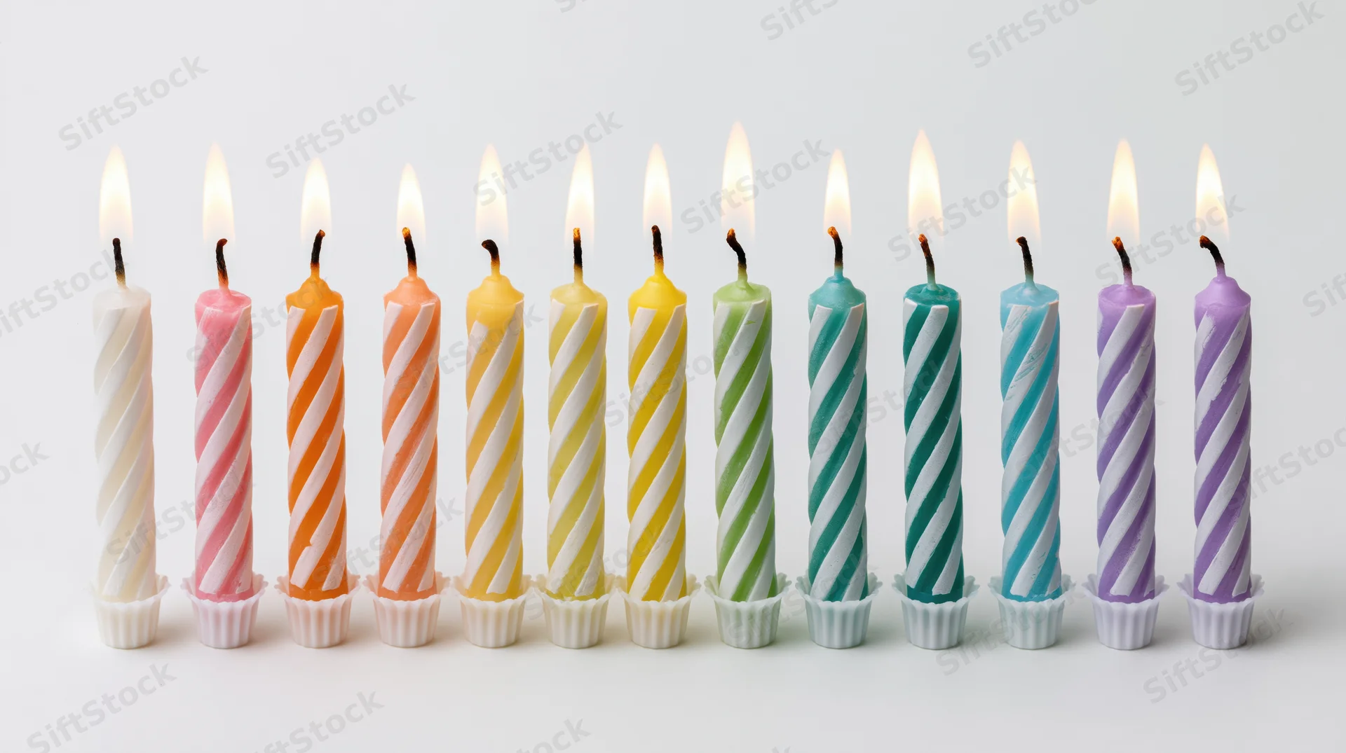 Ten lit birthday candles in a row on a white background