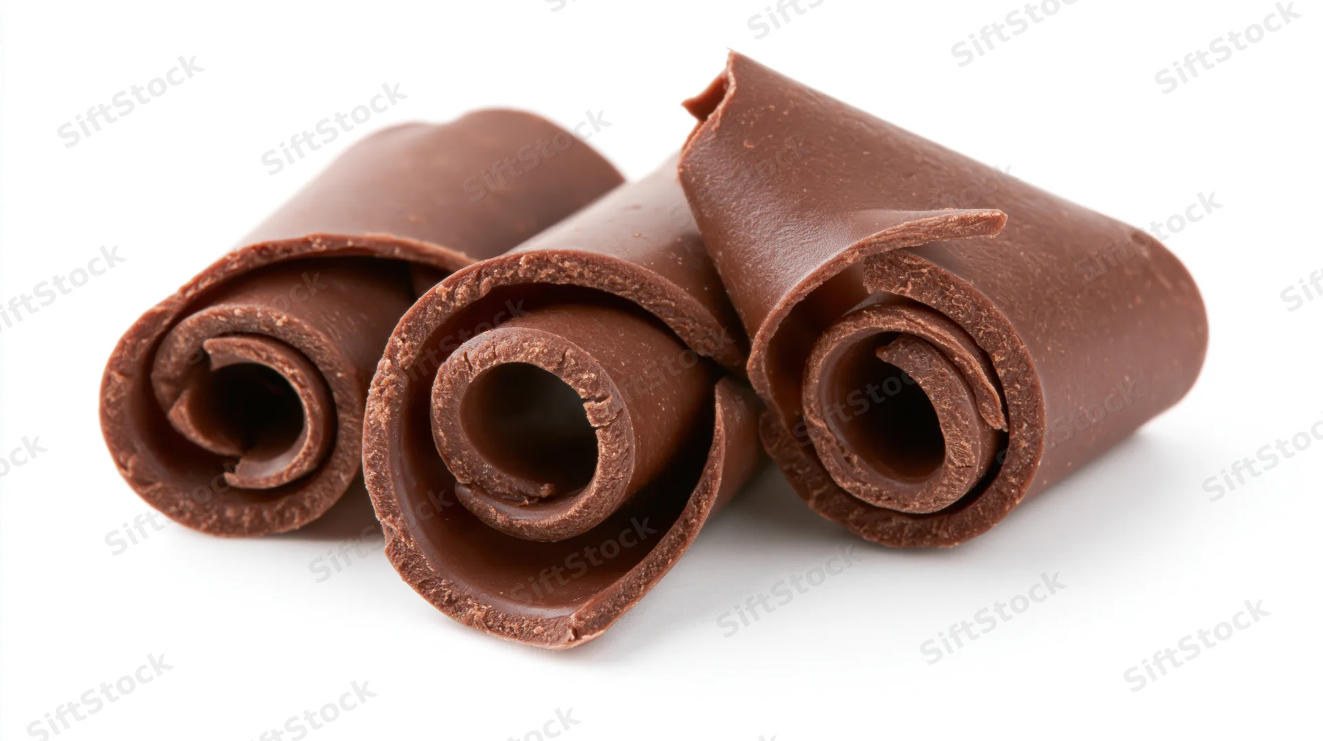 Three dark milk chocolate curls rolled into tight spirals on a white background