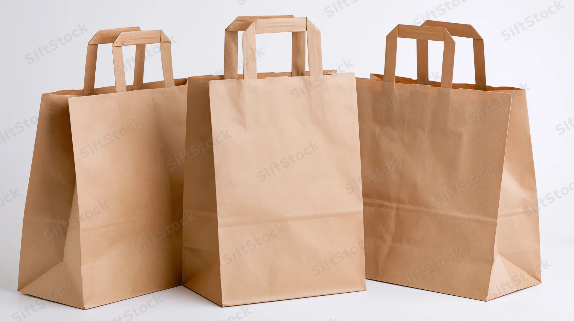 Three plain kraft paper shopping bags with flat folded handles on white background