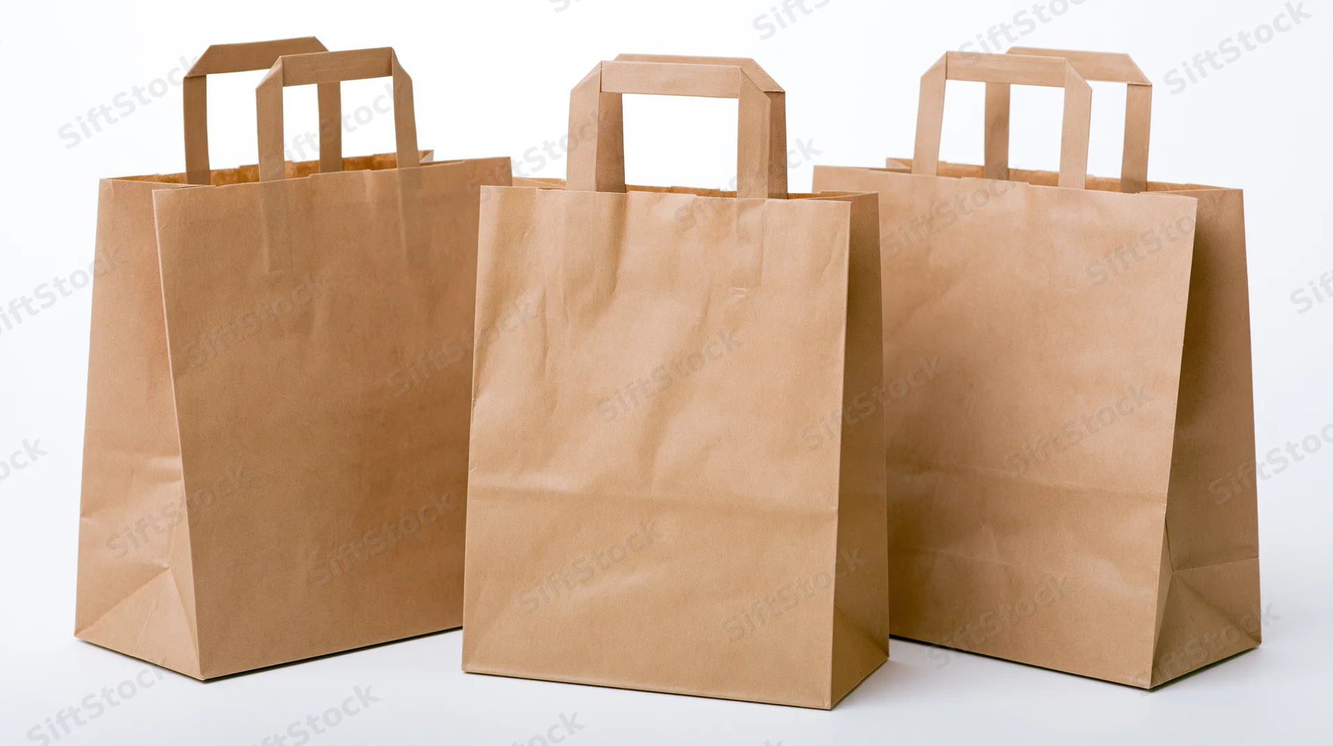 Three plain kraft paper shopping bags with flat folded handles on white background