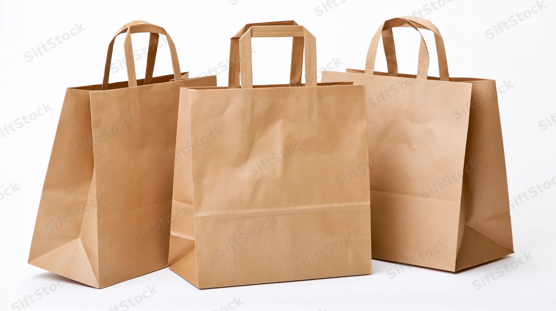 Three plain kraft paper shopping bags with flat folded handles on white background
