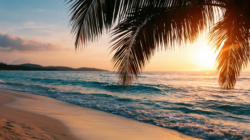 Golden hour sunset over tropical beach with palm fronds framing turquoise waves washing onto sand