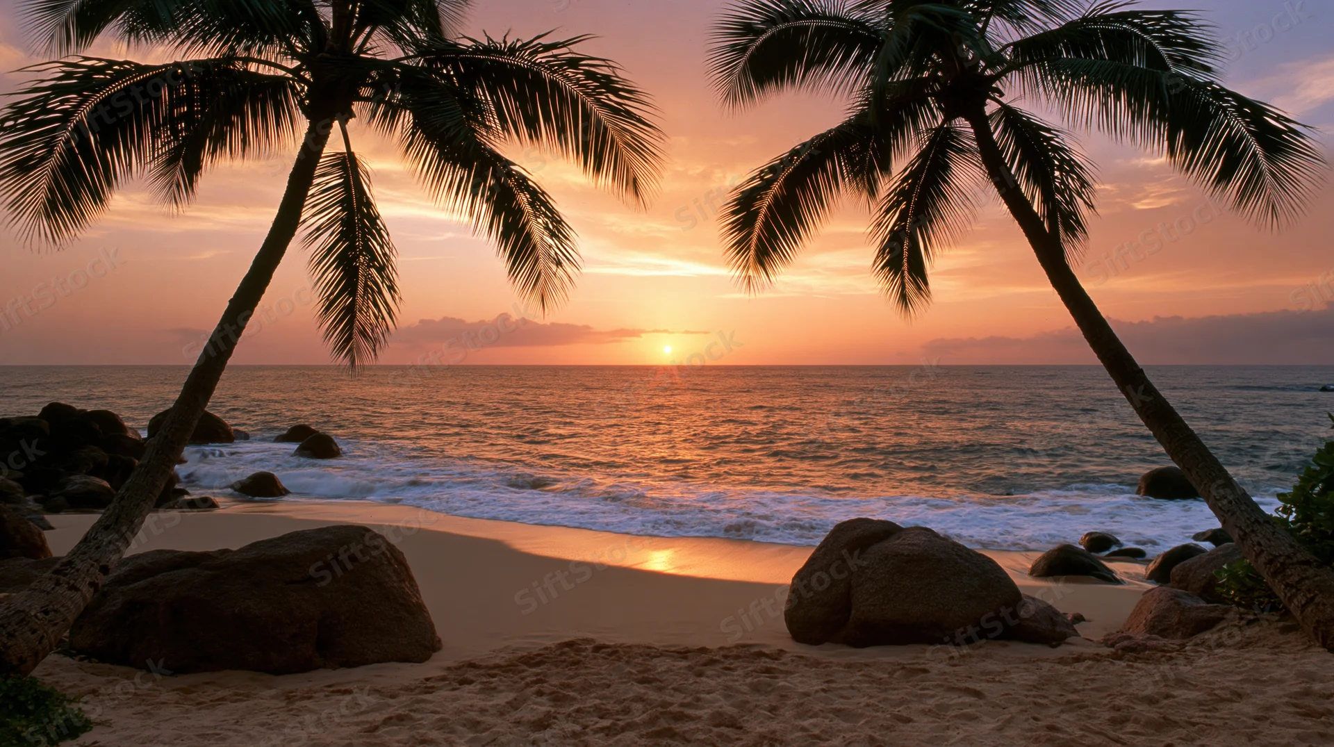 Tropical beach at sunset framed by two leaning coconut palms