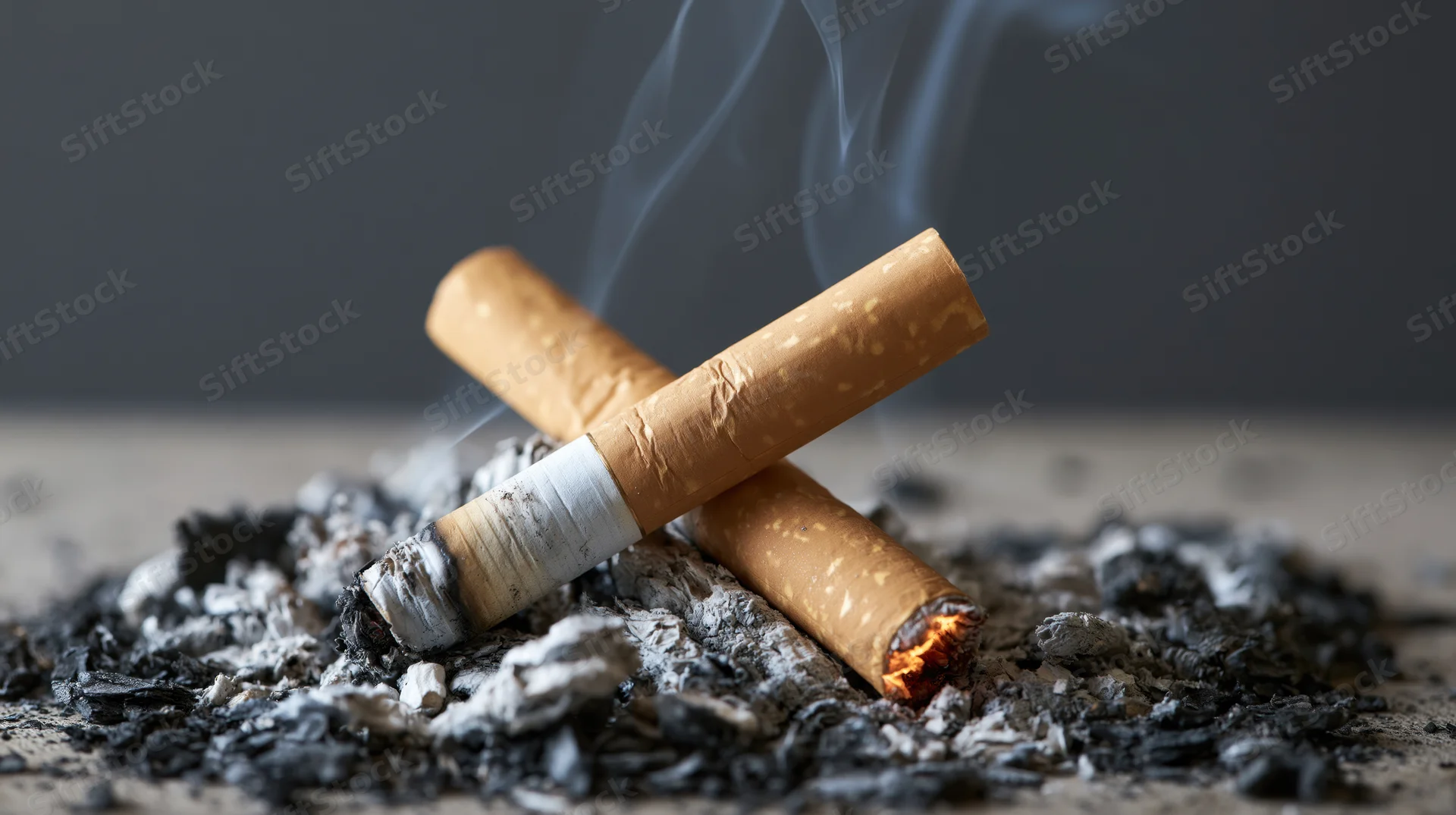 Two cigarette butts crossed and smoldering in a pile of ash
