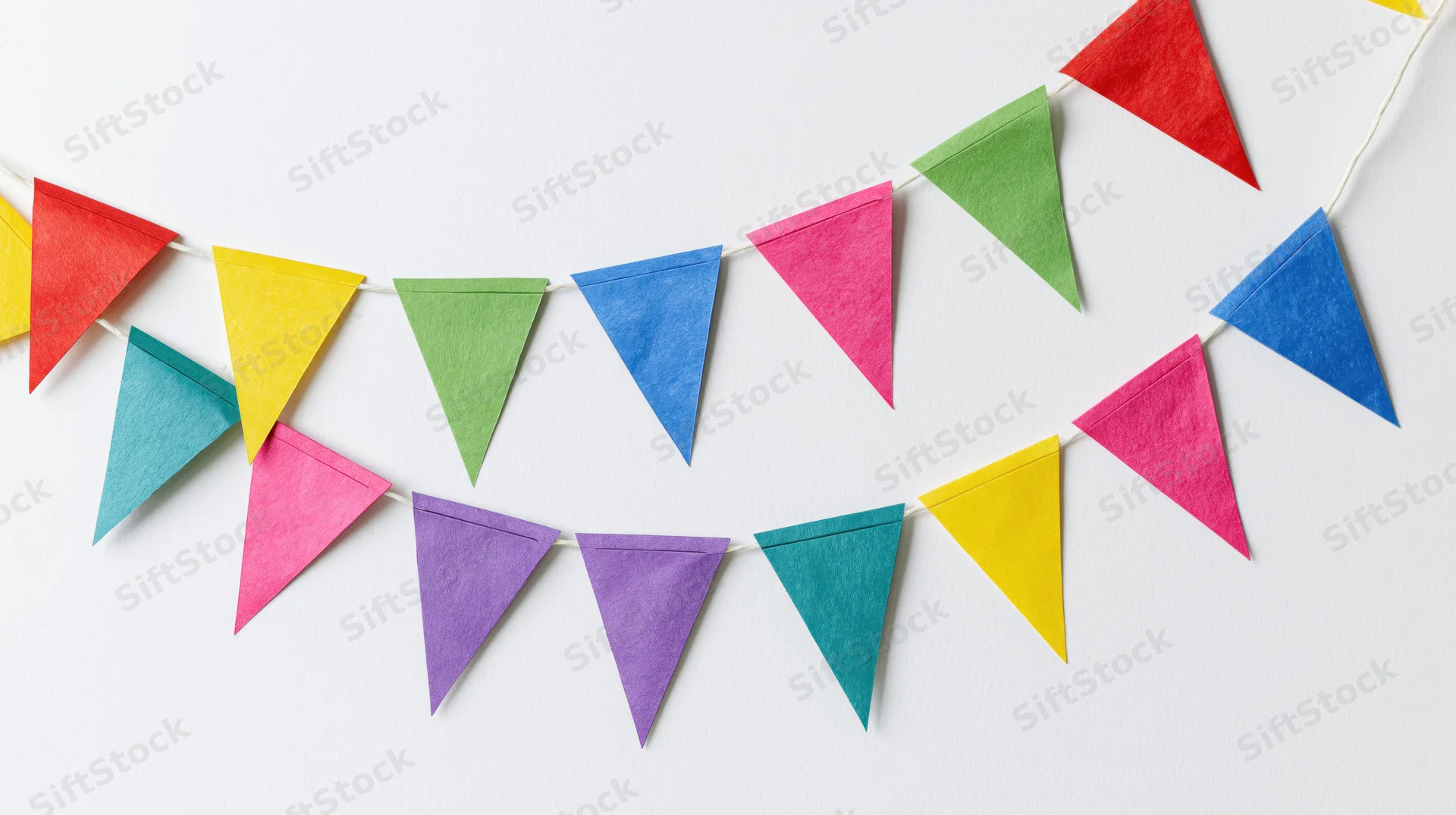 Two strands of colorful triangular paper bunting flags hanging on a white wall