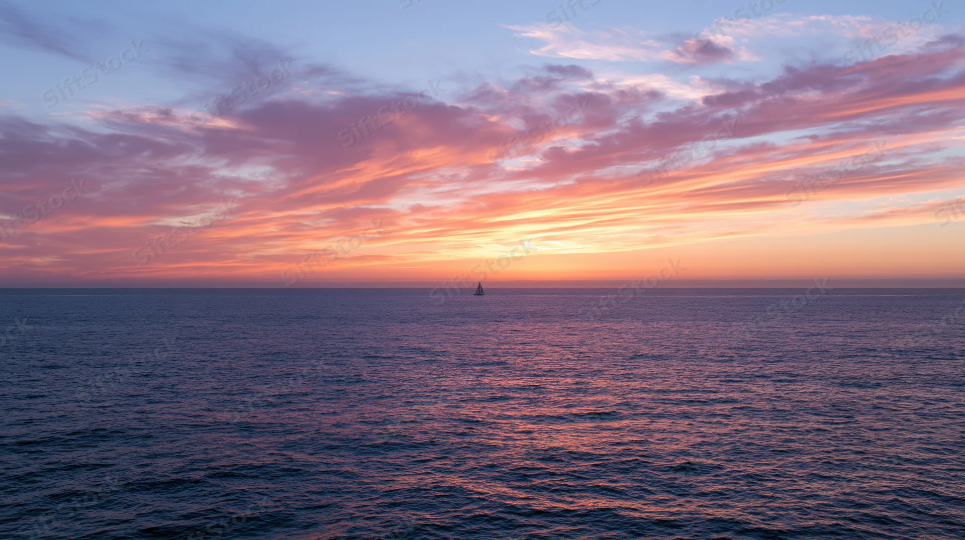 Single sailboat silhouetted on calm ocean at sunset under colorful sky