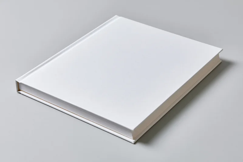 Blank white hardcover book lying flat on light grey matte surface