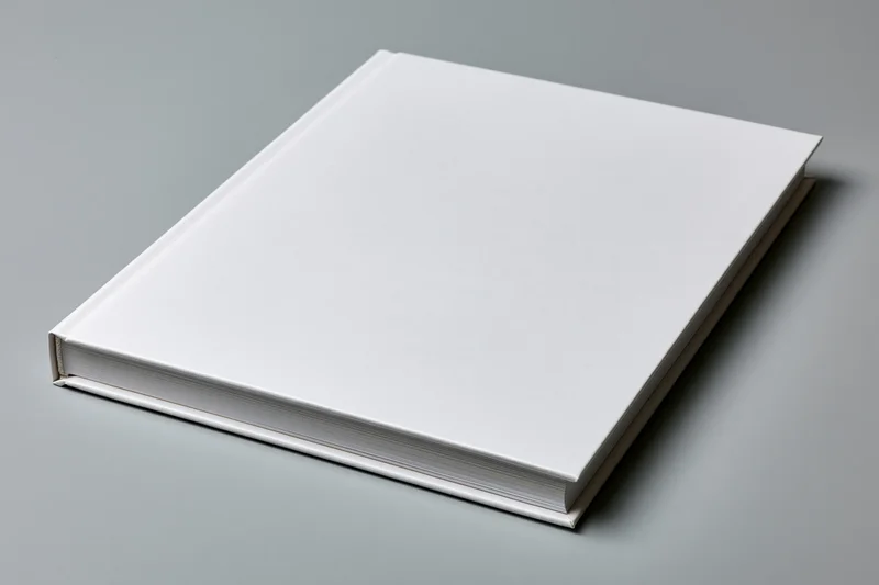Blank white hardcover book lying flat on light grey matte surface