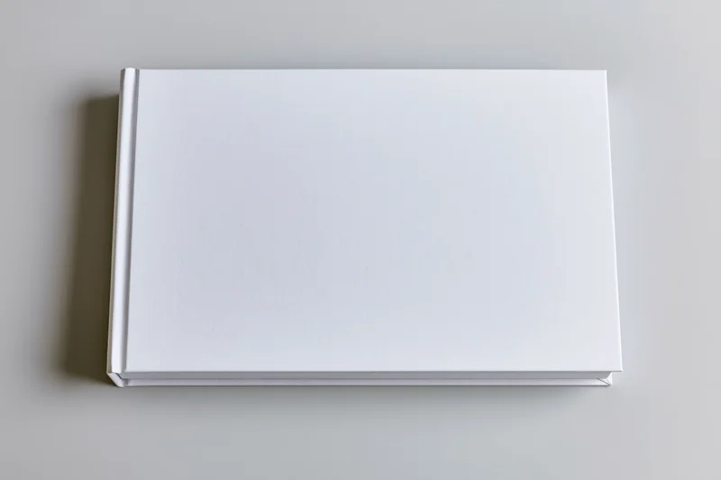 Blank white hardcover book lying flat on a neutral surface