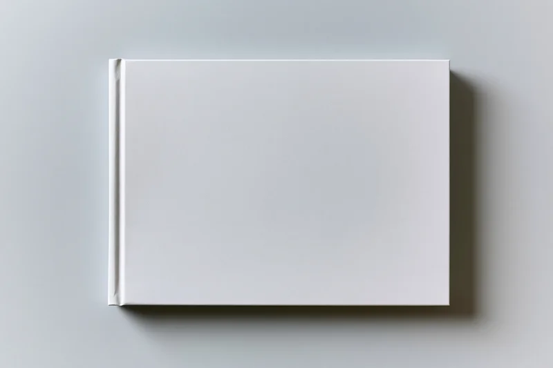 Blank white hardcover book lying flat on a neutral surface