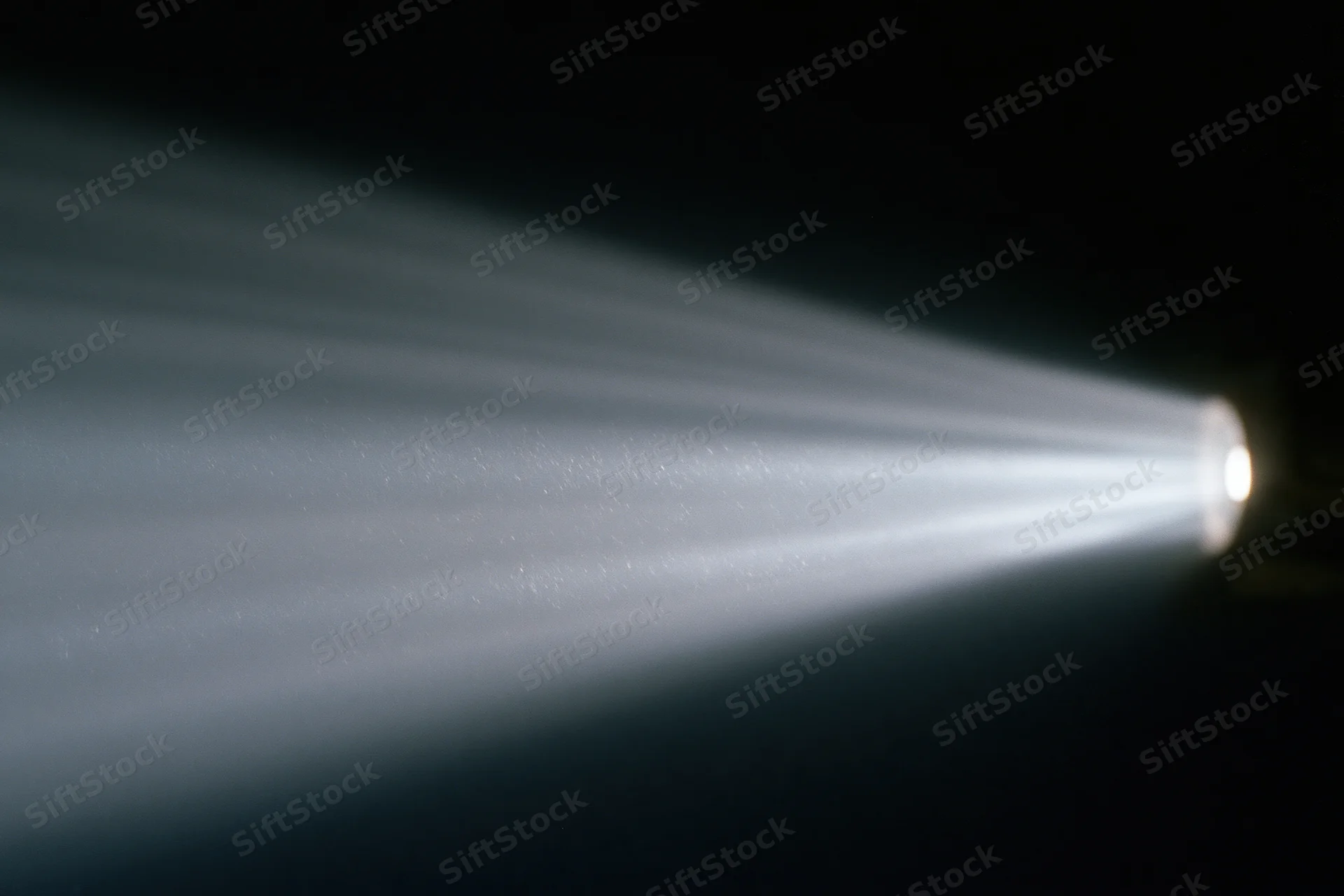 Cinema projector beam cutting through dark room with visible light rays