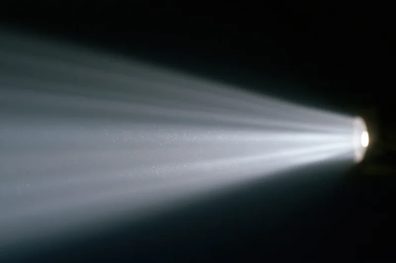Cinema projector beam cutting through dark room with visible light rays