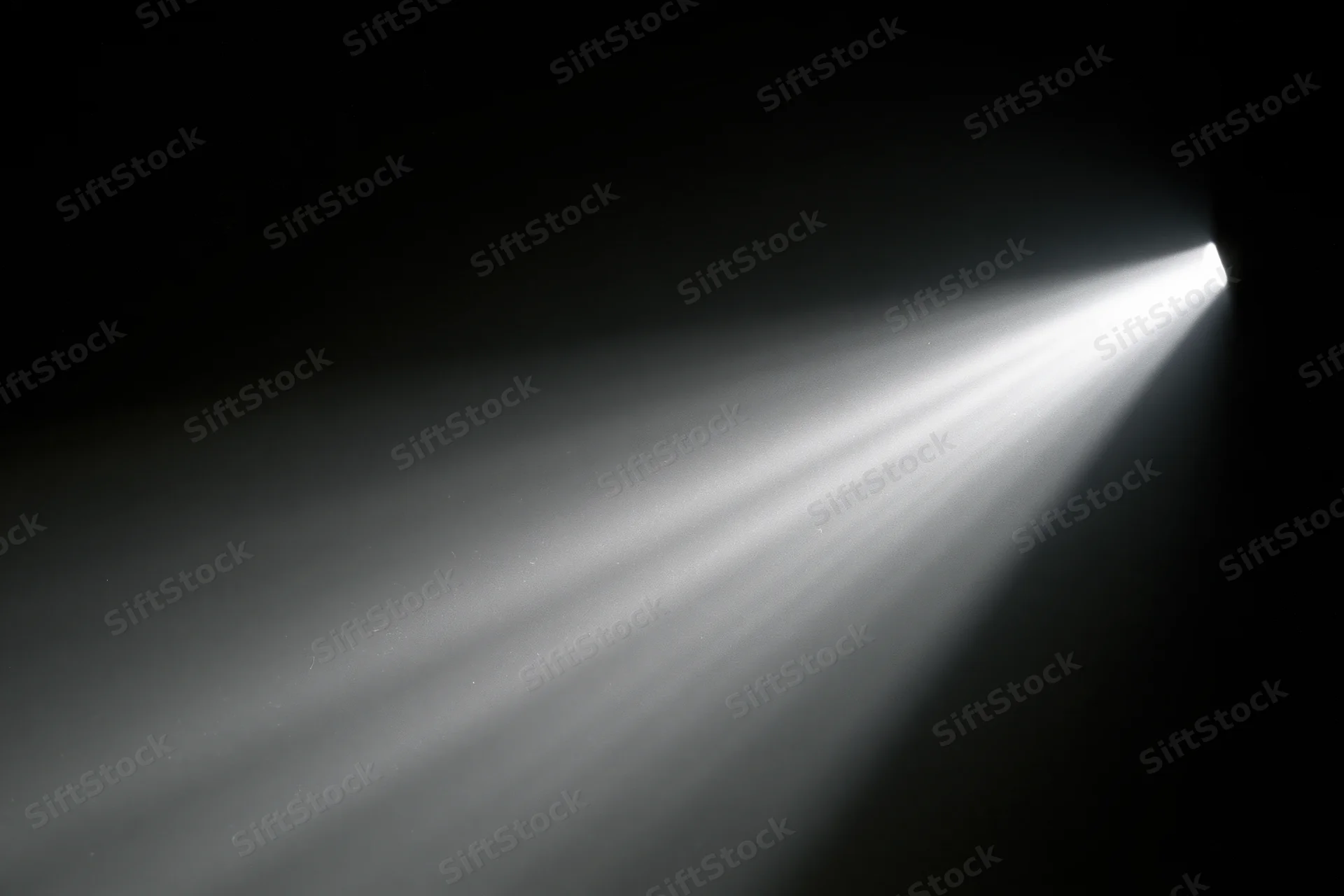 A projector beam cutting through a dark room with visible light rays and shadows